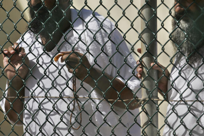 In this photo, reviewed by a US Department of Defense official, detainees stand together at a fence, one holding Islamic prayer beads, at Camp Delta prison, at the Guantanamo Bay U.S. Naval Base, Cuba, on Tuesday, September 19, 2006.