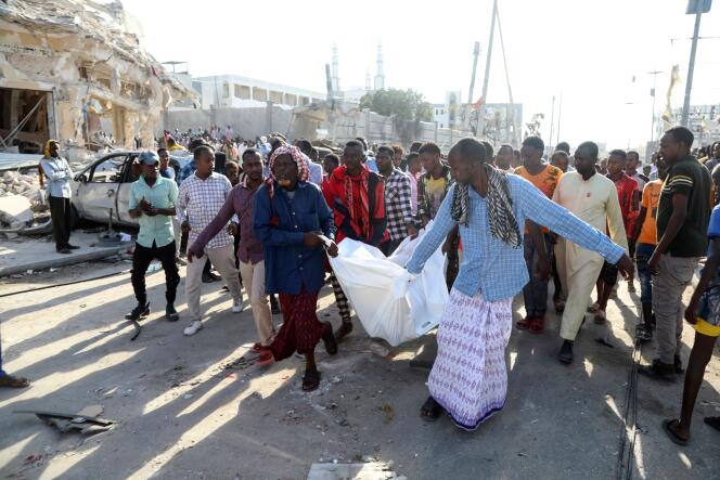 Des habitants transportent le corps d’une victime à Mogadiscio, en Somalie, le 30 octobre 2022, après un attentat à la voiture piégée contre le ministère de l’Éducation, le 29 octobre 2022.
