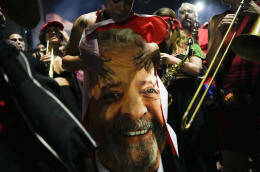 A supporter of former Brazilian President Luiz Inacio Lula da Silva holds a flag emblazoned with da Silva's face after results in the presidential run-off election were announced, in Sao Paulo, Brazil, Sunday, Oct. 30, 2022. Brazil's electoral authority said that da Silva defeated incumbent Jair Bolsonaro to become the country's next president. (AP Photo/Matias Delacroix)