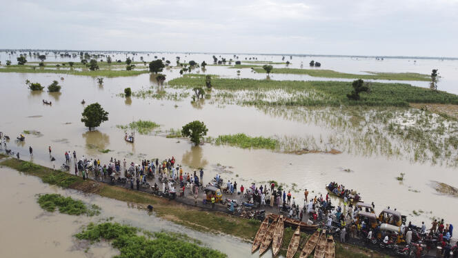 Des personnes marchent dans les eaux de crue et les terres agricoles inondées après de fortes pluies à Hadeja, au Nigeria, le 19 septembre 2022. 
