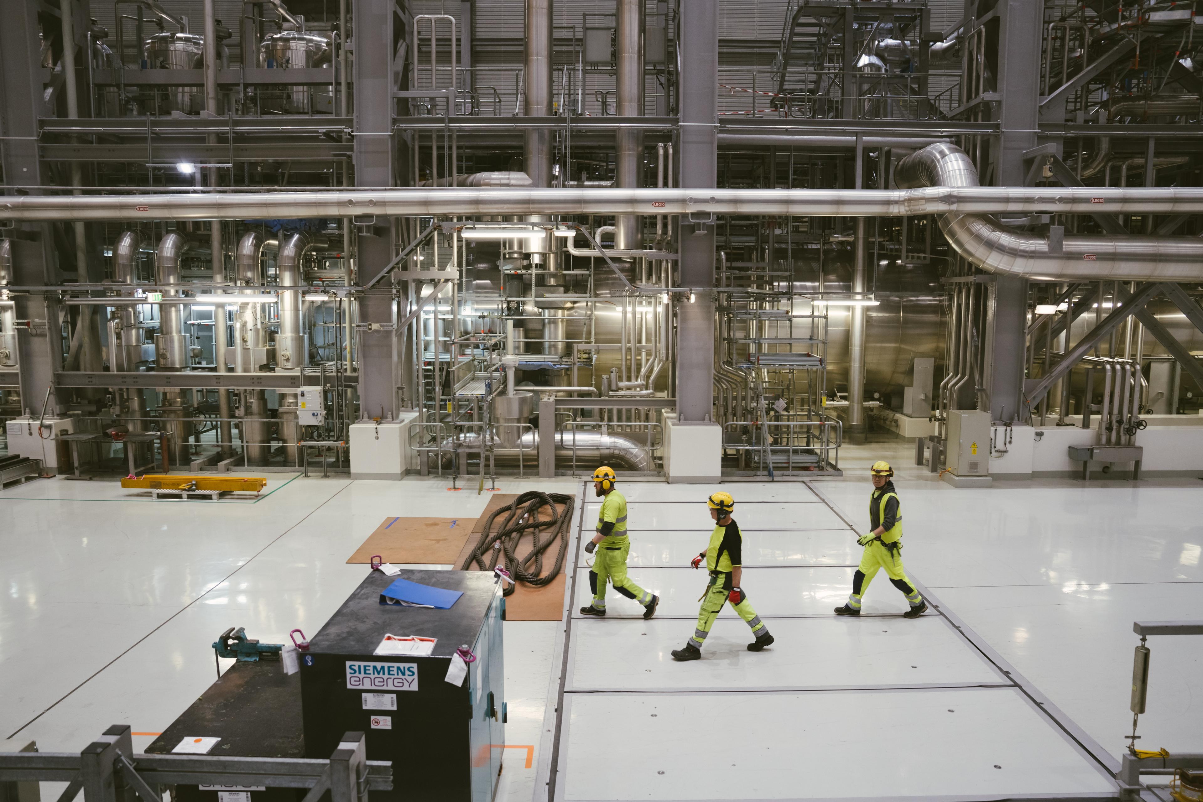 Des ouvriers traversent la salle des turbines du réacteur nucléaire d’Olkiluoto 3.