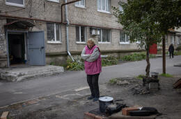 Ukraine, Lyman, le 21 octobre 2022. La ville a été reprise par les ukrainiens courant septembre 2022. Il n'y a pas d'électricité, de gaz ni chauffage ou d'eau courante à Lyman. Des habitants vivent pourtant toujours là bas et se préparent à affronter l'hiver. Svetlana, fait chauffer de la nourriture devant chez elle.