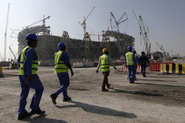 Des ouvriers marchent jusqu’au stade de Lusail, la plus grande des huit enceintes qui doivent accueillir les matchs de la Coupe du monde 2022, construite dans la ville homonyme au nord de Doha, le 20 décembre 2019.