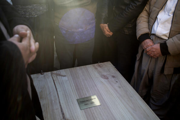 RANIA, IRAQ - DECEMBER 26: Men gather over the body of Shakar Ali Pirot in his wooden coffin, waiting to be washed and prepared for burial on December 26, 2021 in Rania, Iraq. His body was returned to the Kurdistan Region of Iraq with 15 others who also suffered a tragic death in the English Channel. A migrant boat bound for Britain carrying 34 people from different nationalities capsized on November 24 on the English Channel between France and Britain, out of which there are only two known survivors. The bodies were taken to Calais port, of which 16 were returned to the Kurdistan region of Iraq. Tens of thousands of people have migrated from the Kurdistan Region of Iraq seeking a more stable and better life for themselves and their families. More than 26,700 people have taken the dangerous journey by boat to the UK this year. (Photo by Hawre Khalid/Getty Images) (Photo by Hawre Khalid / GETTY IMAGES EUROPE / Getty Images via AFP)
