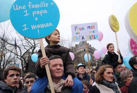 Protestors hold placards reading " A family, 1 dad + 1 mom'' and ''For me a dad and a mom'' during a demonstration denouncing same-sex marriages on November 17, 2012 in Paris. France's Socialist government on November 7, 2012 adopted a draft law to authorise gay marriage and adoption despite fierce opposition from the Roman Catholic Church and the right-wing opposition. AFP PHOTO THOMAS SAMSON (Photo by THOMAS SAMSON / AFP)