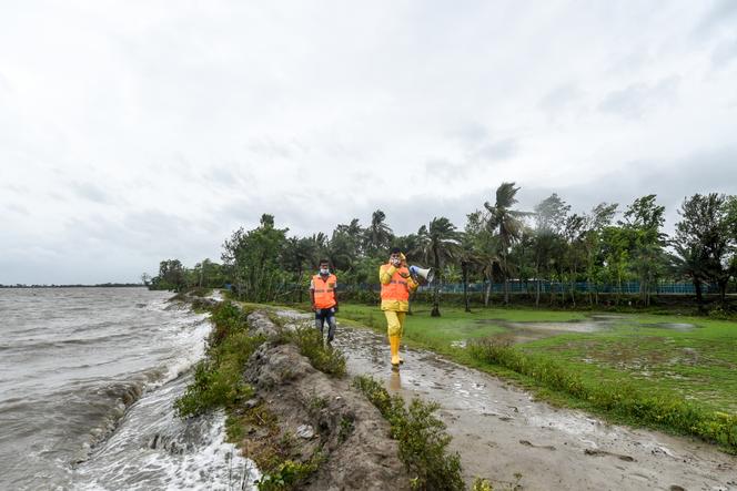 Volunteers of the Cyclone Preparedness Programme (CPP) walk along in an alley as they use a megaphone to urge residents to evacuate to shelters ahead of the expected landfall of cyclone Amphan, in Dacope of Khulna district (Bangladesh) on May 20, 2020.