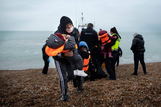 A woman carries her children after being rescued in the Channel by a RNLI lifeboat, at a beach in Dungeness, on the south-east coast of England, on November 24, 2021 