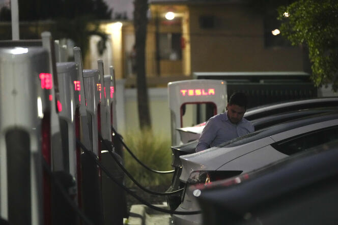 Un automobiliste raccorde sa voiture à une borne de recharge Tesla, à Miami, le 16 novembre 2022.