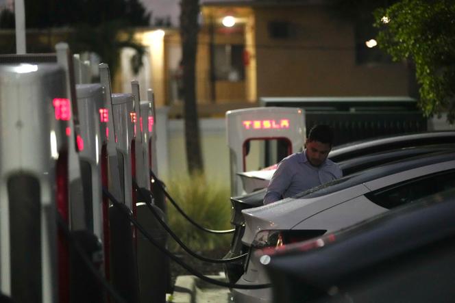 Un automobiliste raccorde sa voiture à une borne de recharge Tesla, à Miami, le 16 novembre 2022.