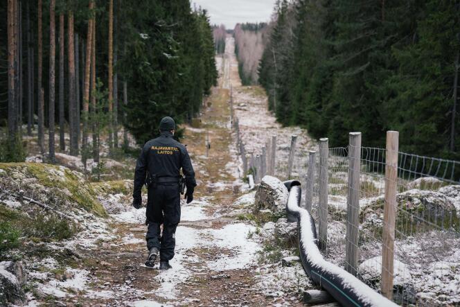 Un garde-frontière finlandais marche le long d’une clôture marquant la frontière entre la Finlande et la Russie, près du poste-frontière de Pelkola, le 18 novembre 2022.