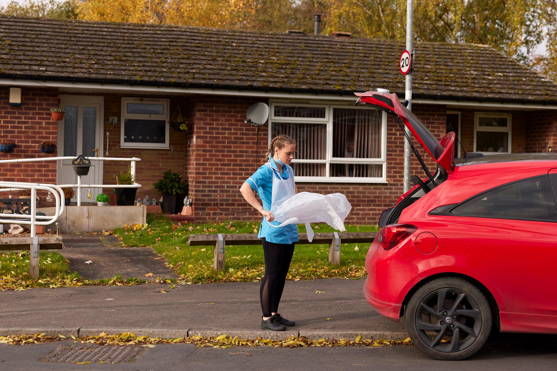 L’aide-soignante de Be Caring Toni Kirlew enfile son tablier avant d’entrer au domicile de sa patiente Sheila Cann, à Leeds, en Angleterre, le 11 novembre 2022.
