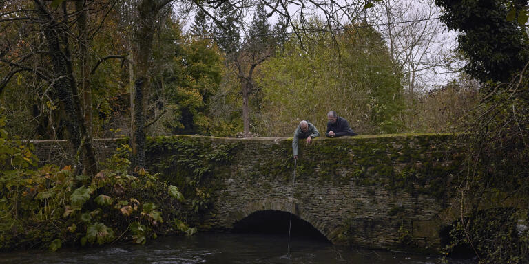 Ashley Smith (left) dips a GoPro camera into the River Windrush in order to monitor its visibility levels as his colleague Peter Hammond (right) looks on in Widford, Oxfordshire.