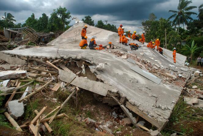 Une équipe de sauveteurs au-dessus d’un bâtiment détruit par le séisme, le 22 novembre 2022 à Cianjur (Indonésie).