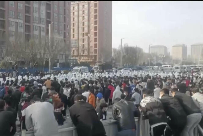 Dalam foto yang diambil pada 23 November 2022 ini, pengunjuk rasa menghadapi petugas keamanan yang mengenakan pakaian pelindung putih di kompleks pabrik Grup Teknologi Foxconn, yang merakit sebagian besar iPhone Apple, di Zhengzhou, provinsi Henan (Tiongkok tengah). 