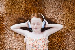 Girl listening to headphones on carpet