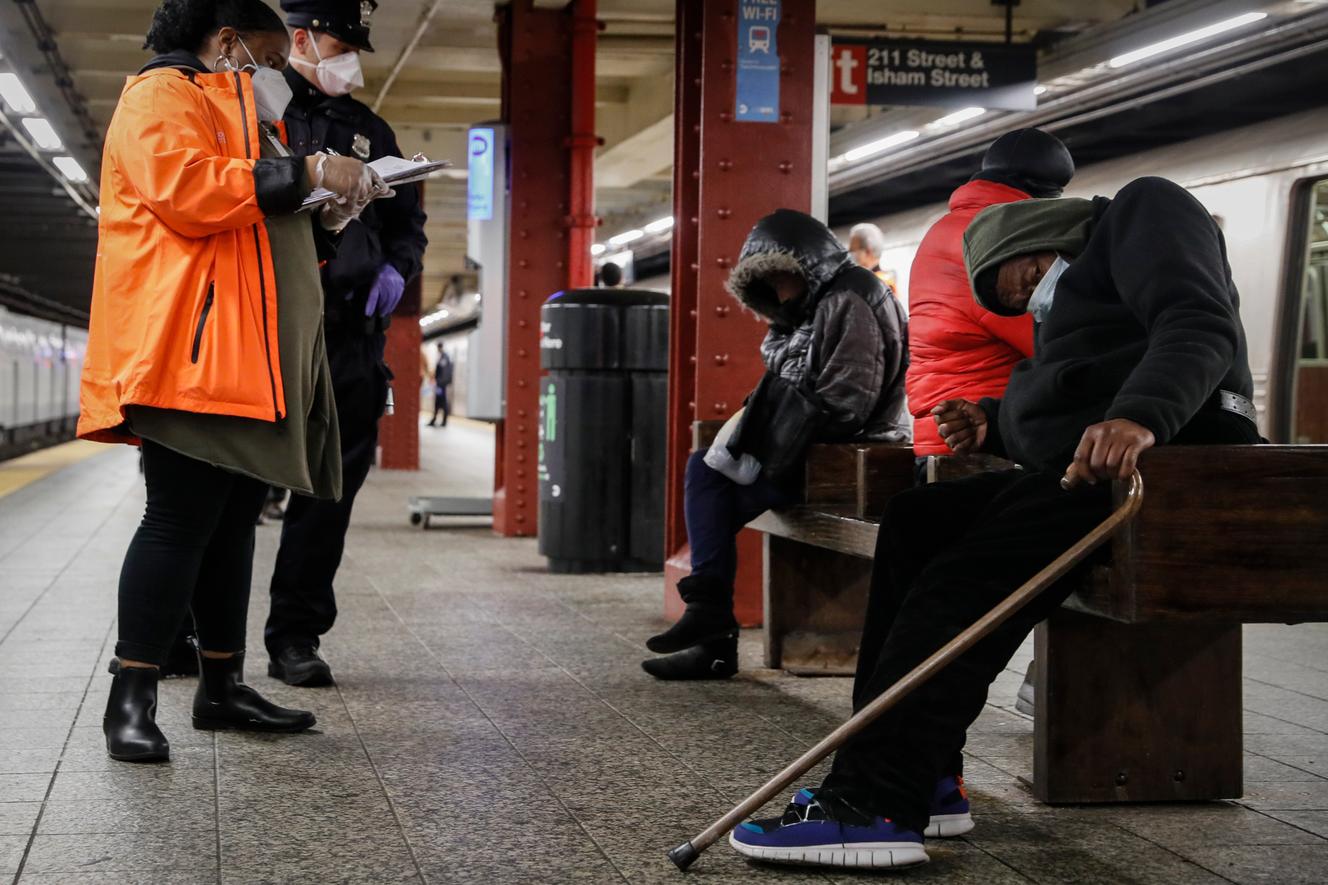 Un travailleur social et un policier viennent en aide à des sans-abri, dans une station de métro de la banlieue de New York, en novembre 2022.