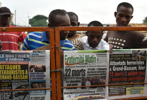 People look at the newspapers covers on March 14, 2016 in Abidjan, a day after gunmen attacked the Ivory Coast resort town of Grand-Bassam, popular with Ivorians and Westerners, killing fourteen civilians and two soldiers. - Al-Qaeda's North African affiliate claimed the attack. France's Foreign Minister Jean-Marc Ayrault and Interior Minister Bernard Cazeneuve will visit Ivory Coast on March 15 in a show of solidarity with the country as fears grow of a mounting jihadist threat in west Africa. (Photo by SIA-KAMBOU / AFP)