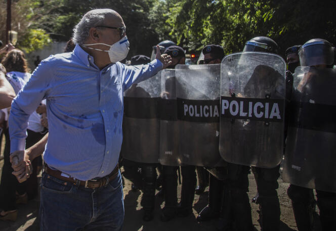Le journaliste nicaraguayen Carlos Fernando Chamorro face à des policiers anti-émeute devant les locaux du média « Confidencial », à Managua, le 14 décembre 2020.
