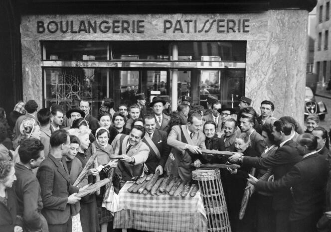 In this file photo taken on October 18, 1948, three Paris city councilors distribute baguette bread, free of charge and without tickets, to customers of a bakery on Boulevard Diderot in Paris.