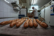 Baker David Buelens puts the baguettes into a basket at a bakery, in Versailles, west of Paris, Tuesday, Nov. 29, 2022.
