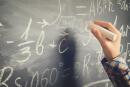 Hand with chalk writting on math formulas black board