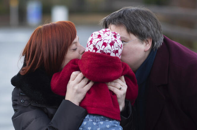 Gesa Teichert-Akkermann (left) and Verena Akkermann kiss their 11-month-old daughter, in Schellerten, Germany, January 12, 2021. 