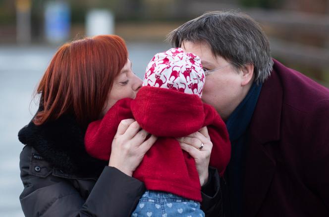 Gesa Teichert-Akkermann (left) and Verena Akkermann kiss their 11-month-old daughter, in Schellerten, Germany, January 12, 2021. 