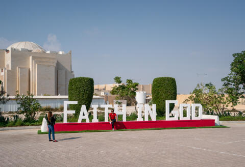 A couple taking photos of the 3D slogan on the church grounds on 7th of December 2022 Doha, Qatar
