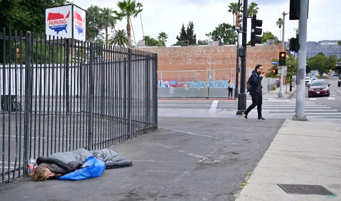 A homeless man sleeps on the floor on the streets of Hollywood on December 1, 2022.