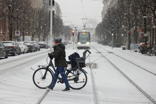 En Estrasburgo, una transeúnte empuja su bicicleta para cruzar la carretera nevada, el miércoles 14 de diciembre de 2022.