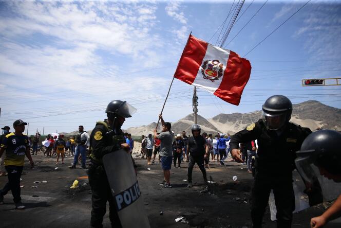 Des partisans du président péruvien destitué Pedro Castillo manifestent sur une autoroute tandis que des policiers arrivent pour dégager les débris, à Chao, dans le nord du Pérou, le 15 décembre 2022.