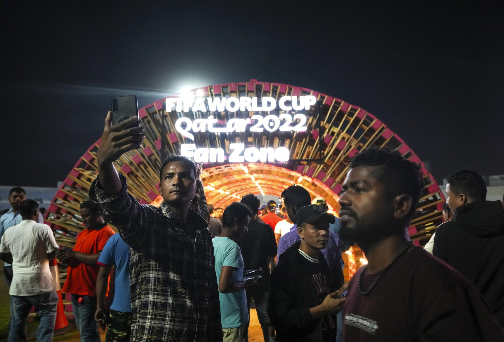Des travailleurs migrants se font photographier avant de regarder un match de football sur un écran géant pendant la Coupe du monde au stade de cricket d’Asian Town, à Doha, au Qatar, le vendredi 2 décembre 2022. 