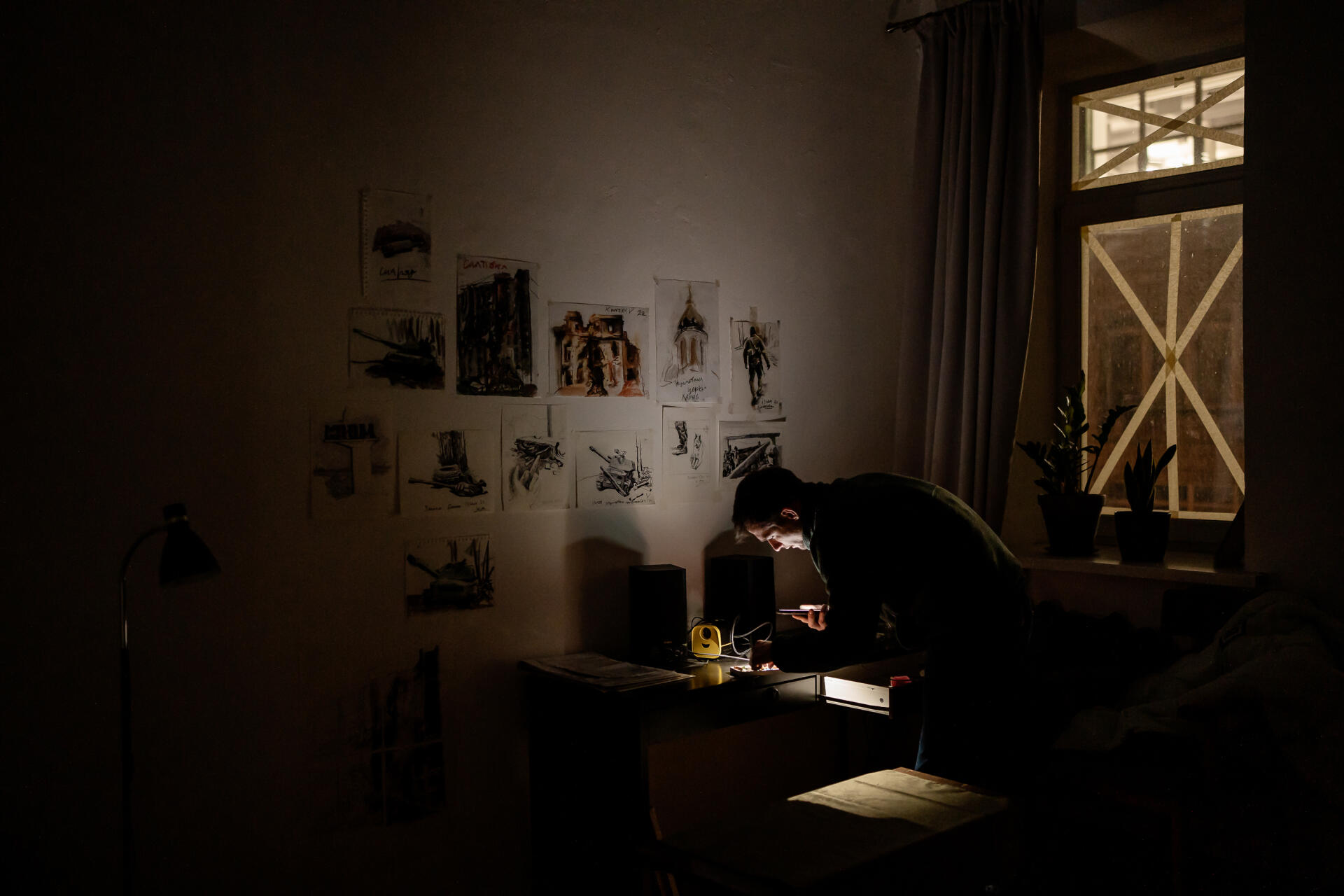 Evgen Klimenko, artiste peintre, cherche ses pastels dans un tiroir de son salon, durant une coupure d’électricité. Ses œuvres sont vendus par la galerie Naked Room pour envoyer de l’équipement aux femmes militaires, et il donne 50 % de ce qu’il vend en direct à un fonds pour les artistes ukrainiens réfugiés. A Kiev, le 19 décembre 2022.
