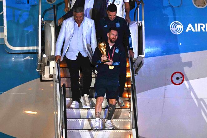 Argentina captain and striker Lionel Messi gets off the plane at Ezeiza airport in the province of Buenos Aires, the FIFA World Cup trophy in hand, Tuesday, December 20, 2022.