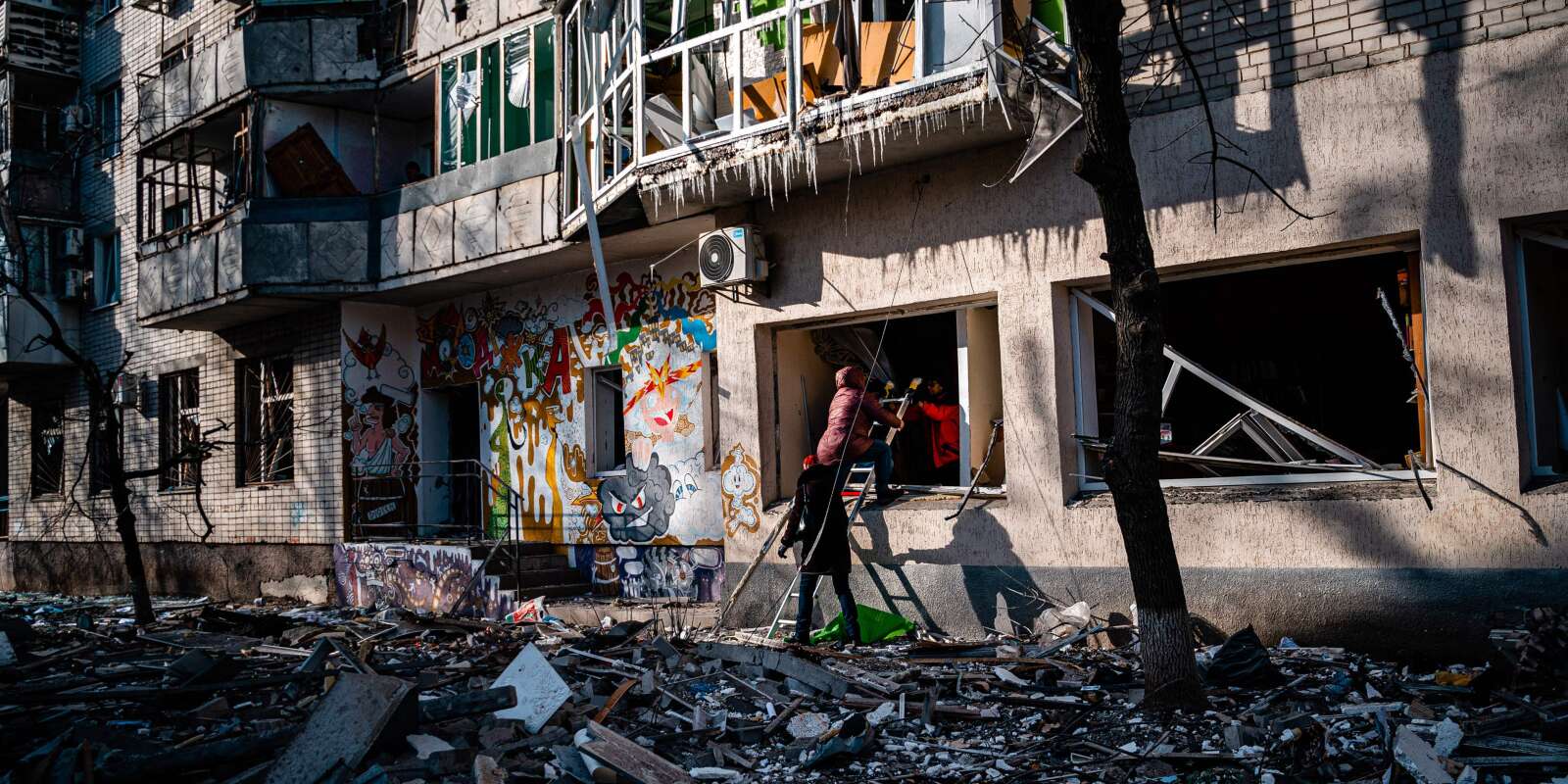 Des habitants utilisent une échelle pour entrer dans un immeuble endommagé par des bombardements russes à Kherson, le 20 décembre 2022.