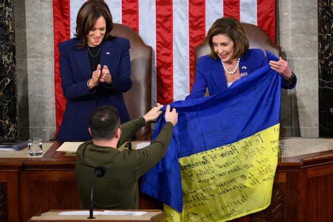 Le président ukrainien Volodymyr Zelensky présente un drapeau national ukrainien à la présidente de la Chambre des États-Unis Nancy Pelosi (à droite) sous le regard de la vice-présidente américaine Kamala Harris lors de son discours devant le Congrès américain à Capitol Hill à Washington, DC, le 21 décembre 2022. .
