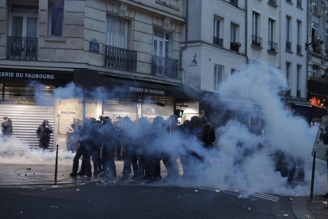 Police officers stand in a cloud of teargas as they clash with members of Kurdish community near the crime scene where a shooting took place in Paris, Friday, Dec. 23, 2022.