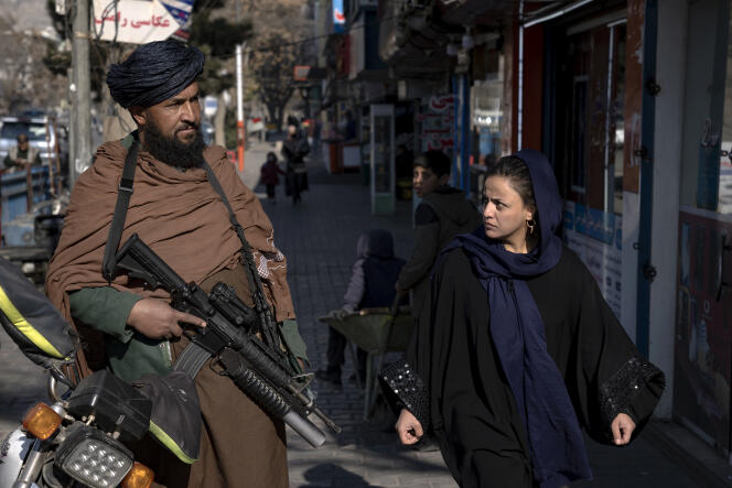 Una mujer pasa junto a un combatiente talibán en una calle de Kabul el 26 de diciembre de 2022.