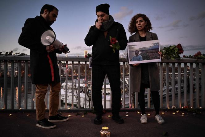 A woman holds a photographic portrait during tribute to Mohammad Moradi, an Iranian man who killed himself after jumping into the Rhone river to raise awareness about the situation of the Iranian people, in Lyon on December 27, 2022.