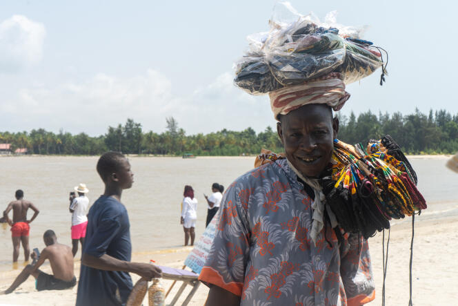 Morou Saadou et ses marchandises sur la plage de La Passe, à l’embouchure de la lagune d’Assinie, en Côte d’Ivoire, le 17 décembre 2022.