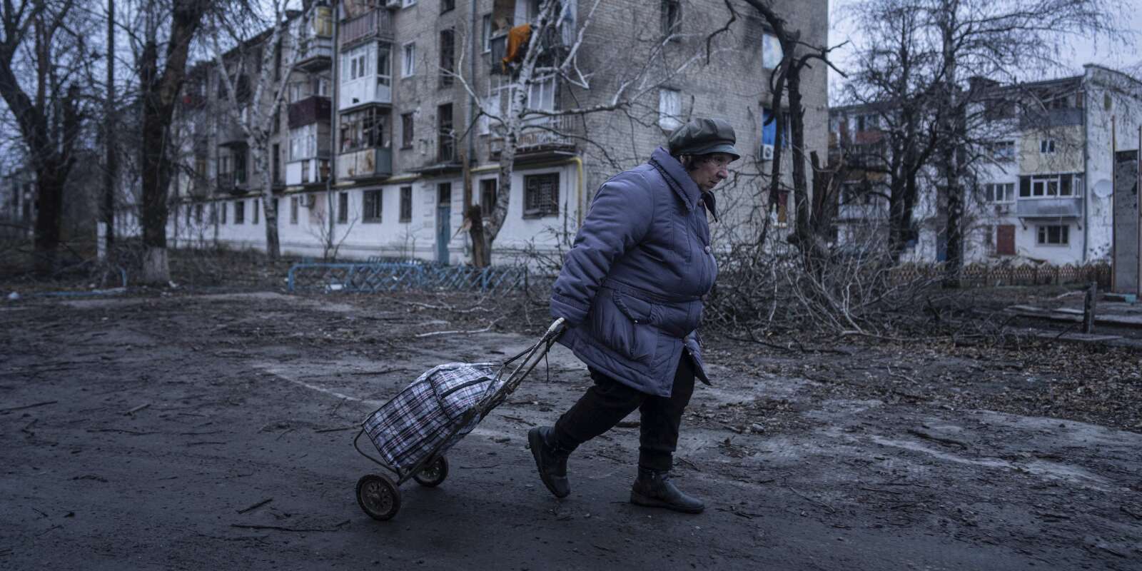 A Koupiansk, dans les environs de Kharkiv, une habitante passe devant des bâtiments détruits par les bombardements russes, 28 décembre 2022. 