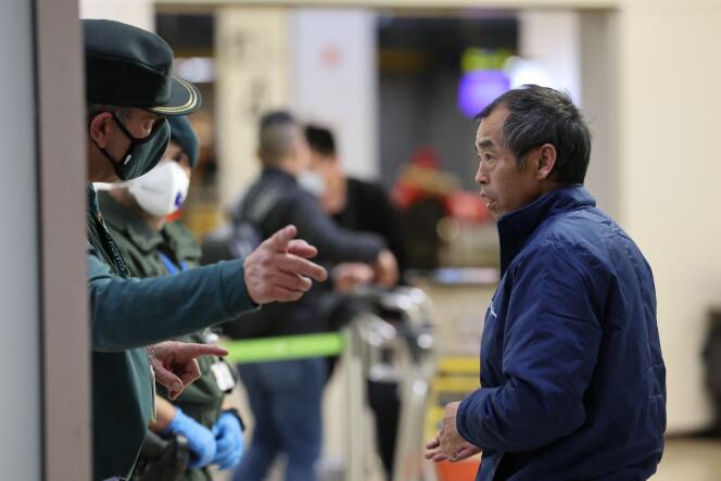 Un pasajero de un vuelo procedente de Pekín escucha las instrucciones de un guardia civil español, el sábado 31 de diciembre de 2022, en el aeropuerto de Madrid. 