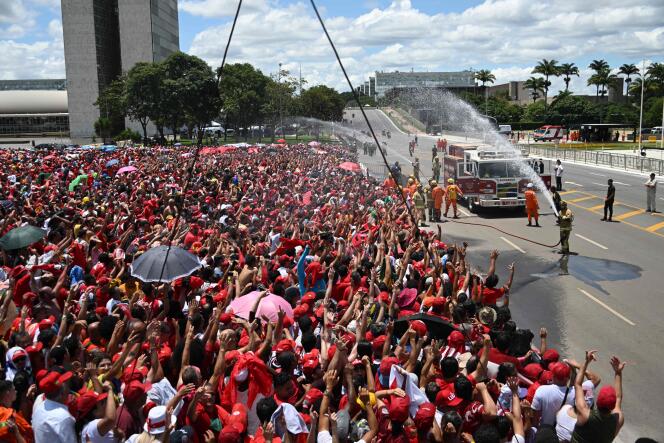 Des pompiers arrosent des partisans de Lula avant la cérémonie d’investiture, le 1er janvier 2023, à Brasilia.