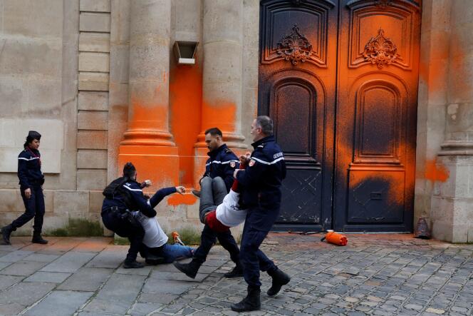 Los gendarmes que garantizan la seguridad de Matignon evacuan a los activistas medioambientales que acudieron a rociar con pintura naranja la entrada del edificio, el 4 de enero de 2023, en París.
