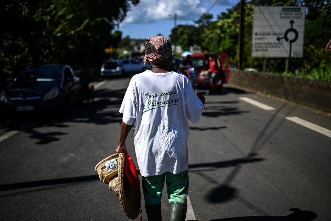 Une femme portant un teeshirt où on peut lire « Tous contre le Chlordecone » marche vers un barrage routier près de la ville de La Boucan en Guadeloupe, le 29 novembre 2021.