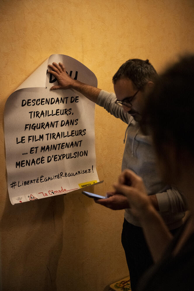 Fabien Arcangeli et Amélie Lambert, des membres du réseau Education sans frontières des Ardennes, présentent une affiche à coller, dans leur appartement de Charleville-Mézières, le 7 janvier 2023.