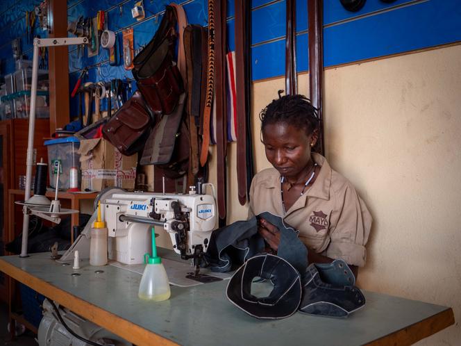 Mary Ina, an employee of Mayo Leather, sews pieces of leather into uppers for children's shoes in Juba on January 10, 2023.
