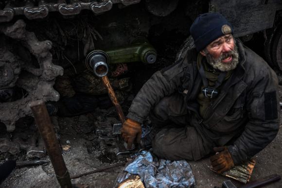 Two mechanics work around the axles of a tank near Greminna on January 12, 2023.