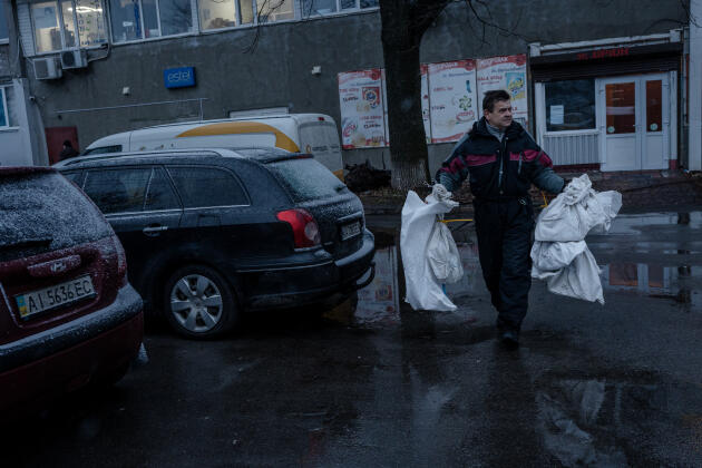 Sergii, chauffeur d’Ukrposhta, porte les sacs de colis qu’il distribuera dans la journée, à Borodianka, en Ukraine, le 6 janvier 2023.