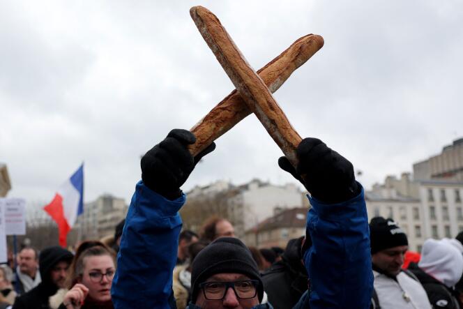 Un hombre cruza dos baguettes de pan en señal de protesta, durante la manifestación organizada por varios colectivos de panaderos artesanales contra el aumento de los precios de la energía, el lunes 23 de enero de 2023 en París.  